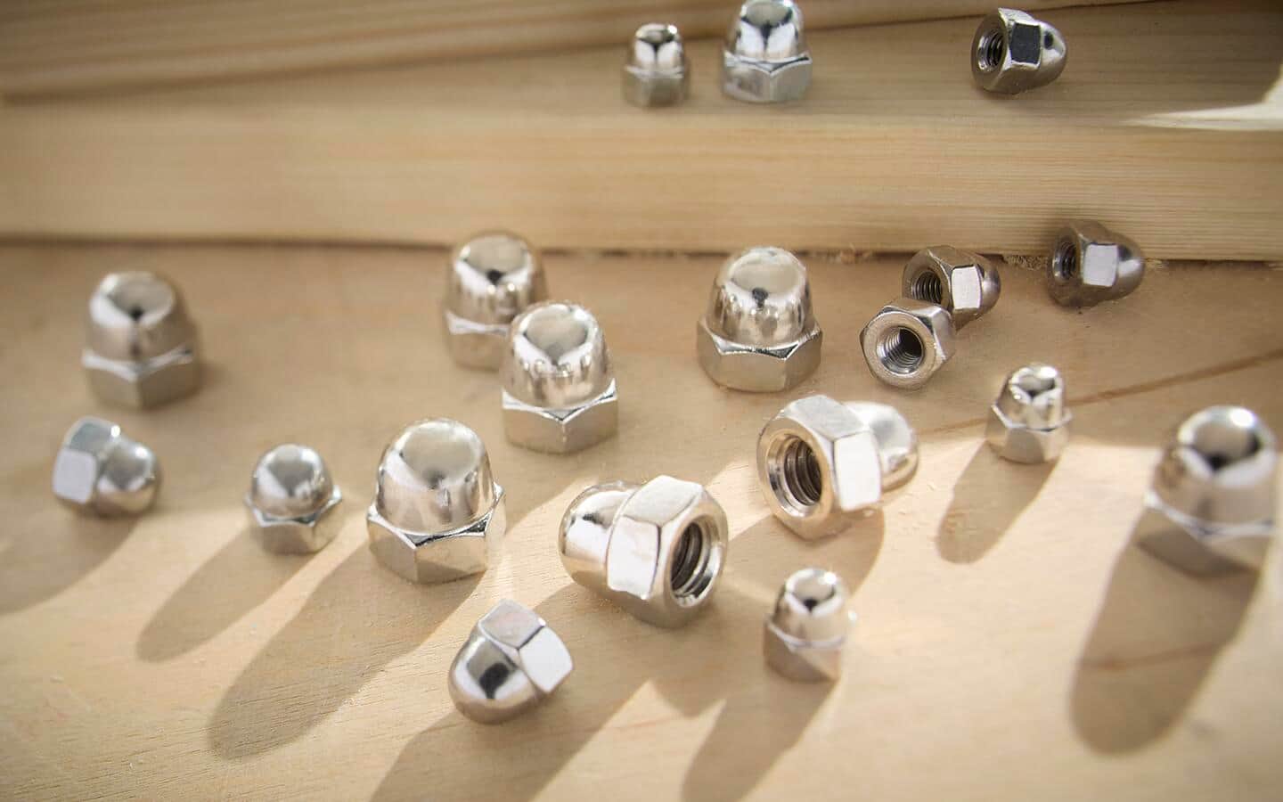 A group of acorn nuts, also known as cap nuts, in various sizes.
