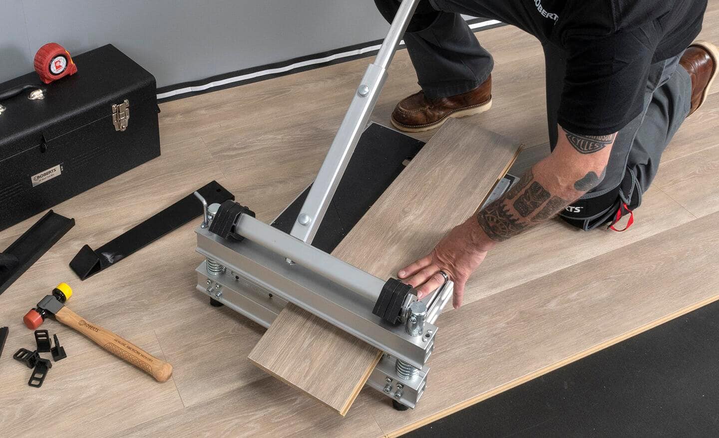 A person uses a vinyl cutter to trim a luxury vinyl plank.