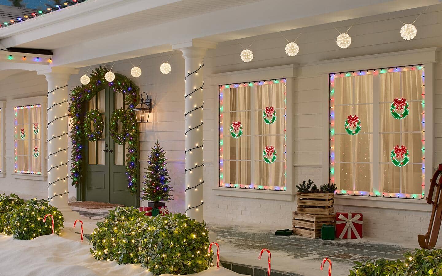A home decorated for the holidays with net lights draped over shrubs and novelty lights hanging in the windows. A home decorated for the holidays with net lights draped over shrubs and novelty lights hanging in the windows.