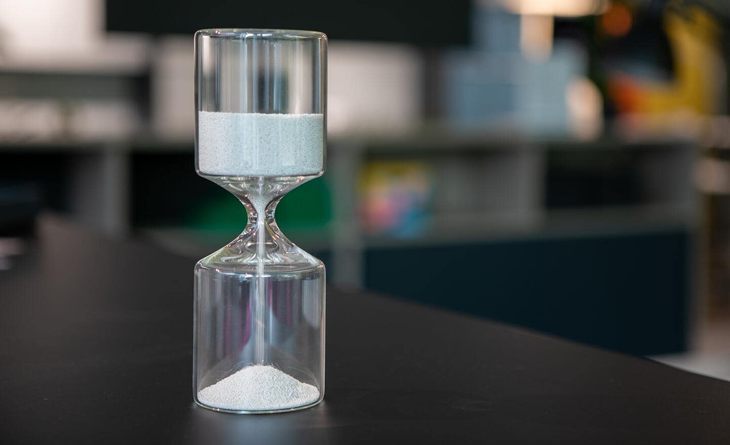 An hourglass on a table depicts the passage of time.