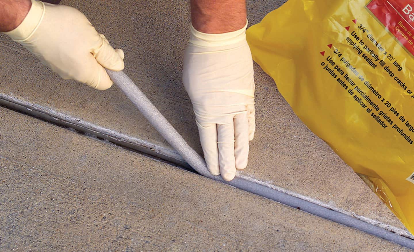 A person inserting a concrete backer rod in between concrete slabs.