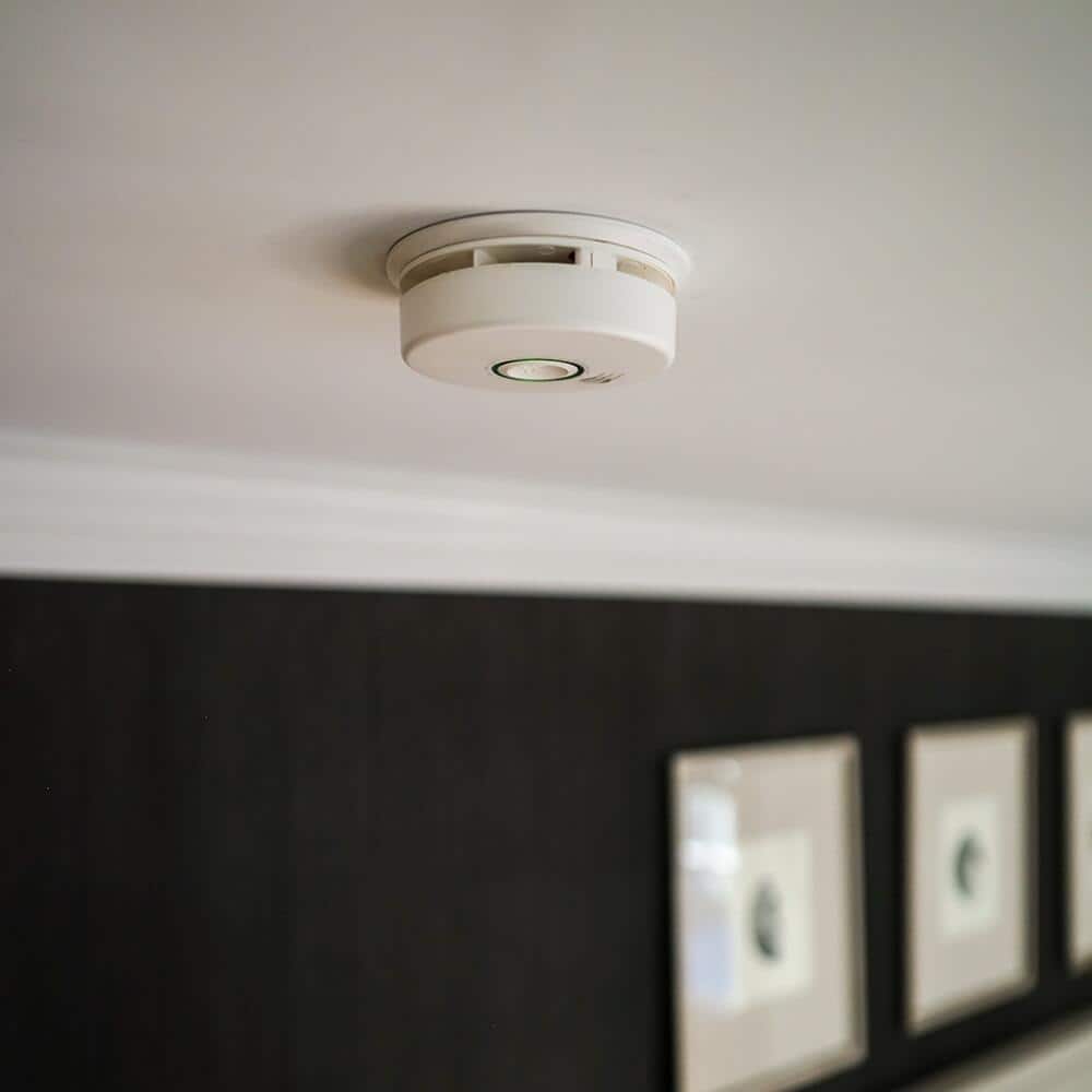 A carbon monoxide detector on a ceiling in a home.