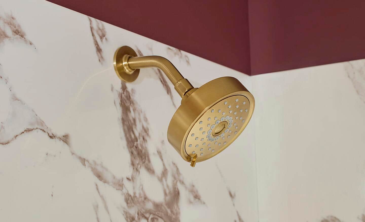 A round, wall-mounted shower head in a brushed gold finish. A round, wall-mounted shower head in a brushed gold finish.