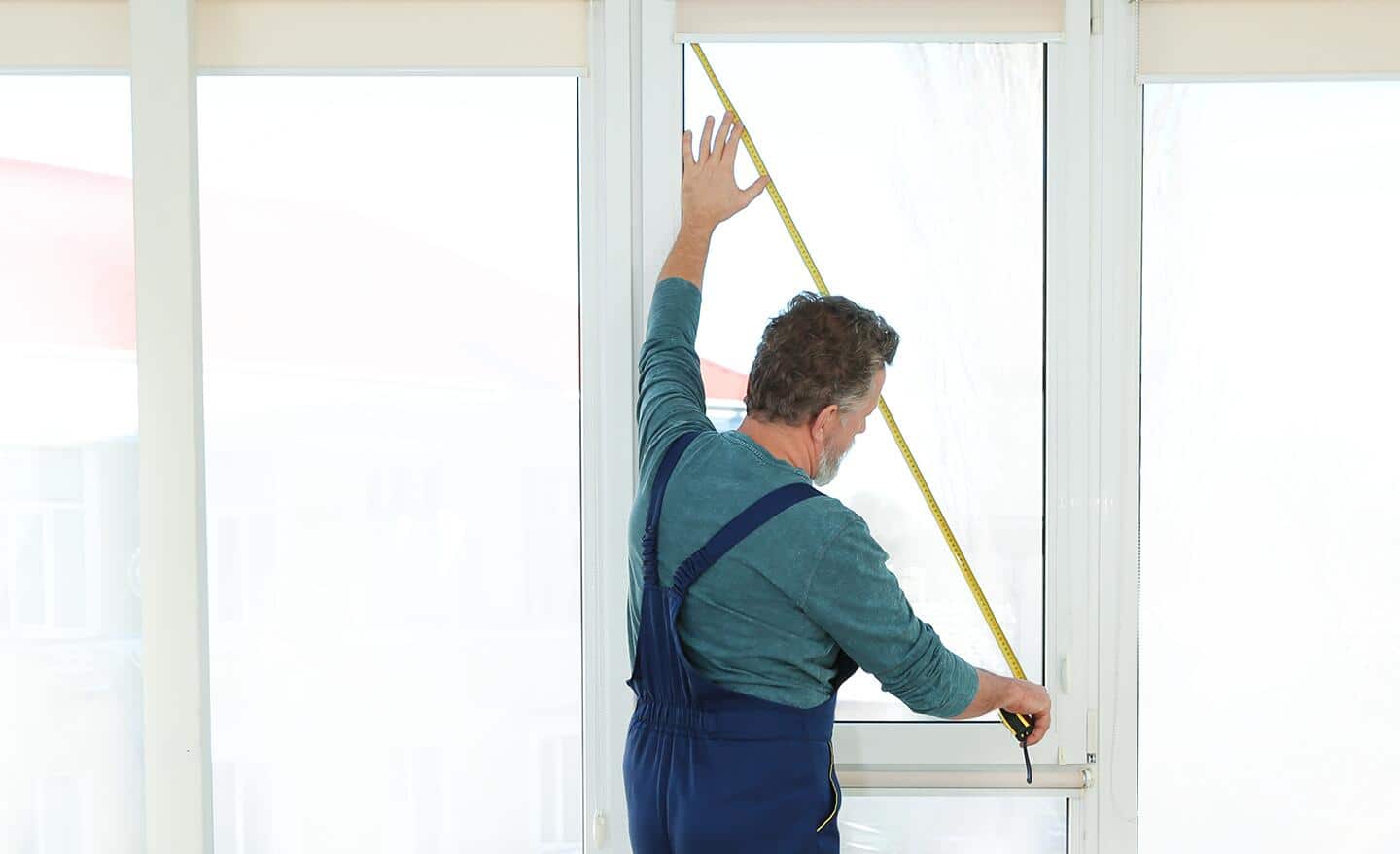 A person measures a window diagonally. 