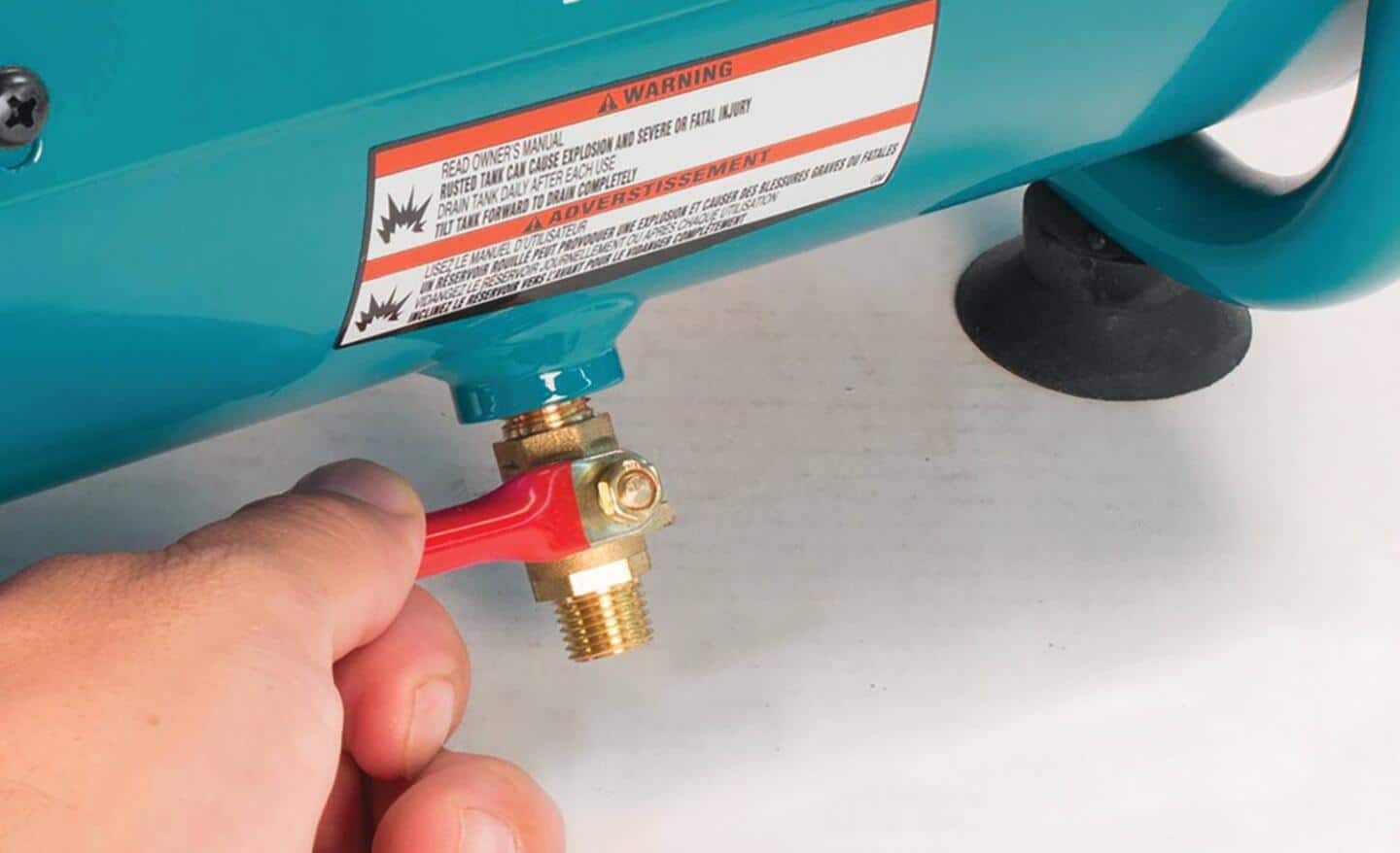 Someone checking the drain valve on an air compressor. Someone checking the drain valve on an air compressor.
