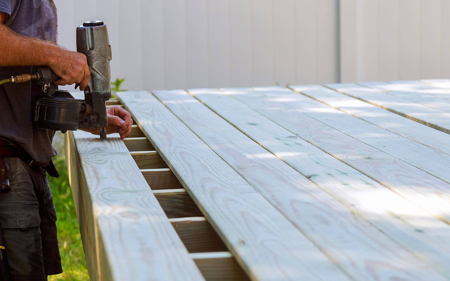 Person drills screws into board on a deck