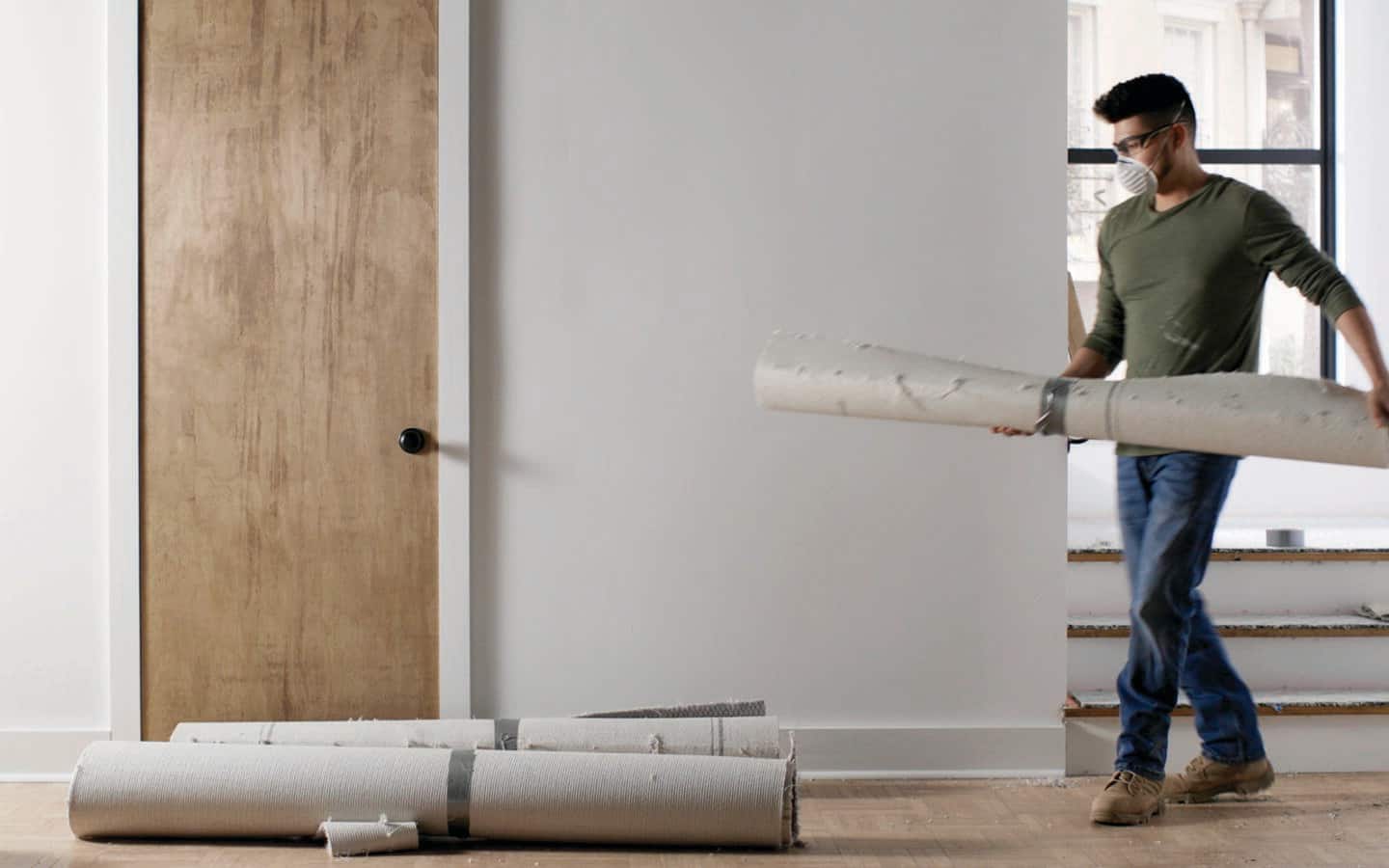 A person carrying rolled up carpet. A person carrying rolled up carpet.