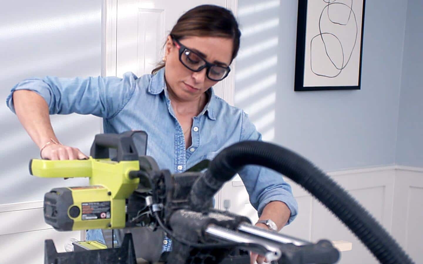 A person using a miter saw to cut wood for a DIY bookshelf. A person using a miter saw to cut wood for a DIY bookshelf.