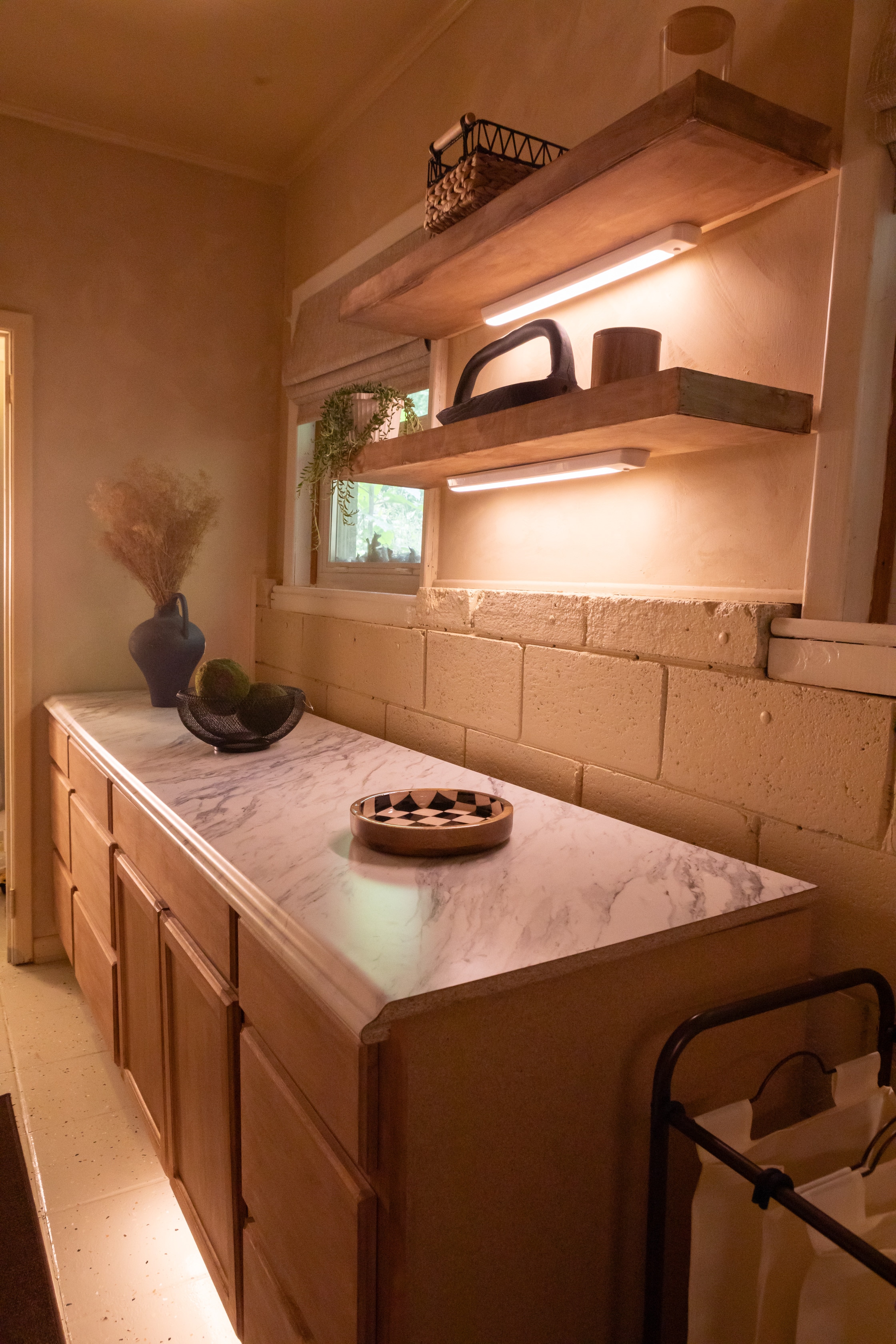 Cabinet storage and wall-mounted wooden shelving in a newly renovated laundry room.
