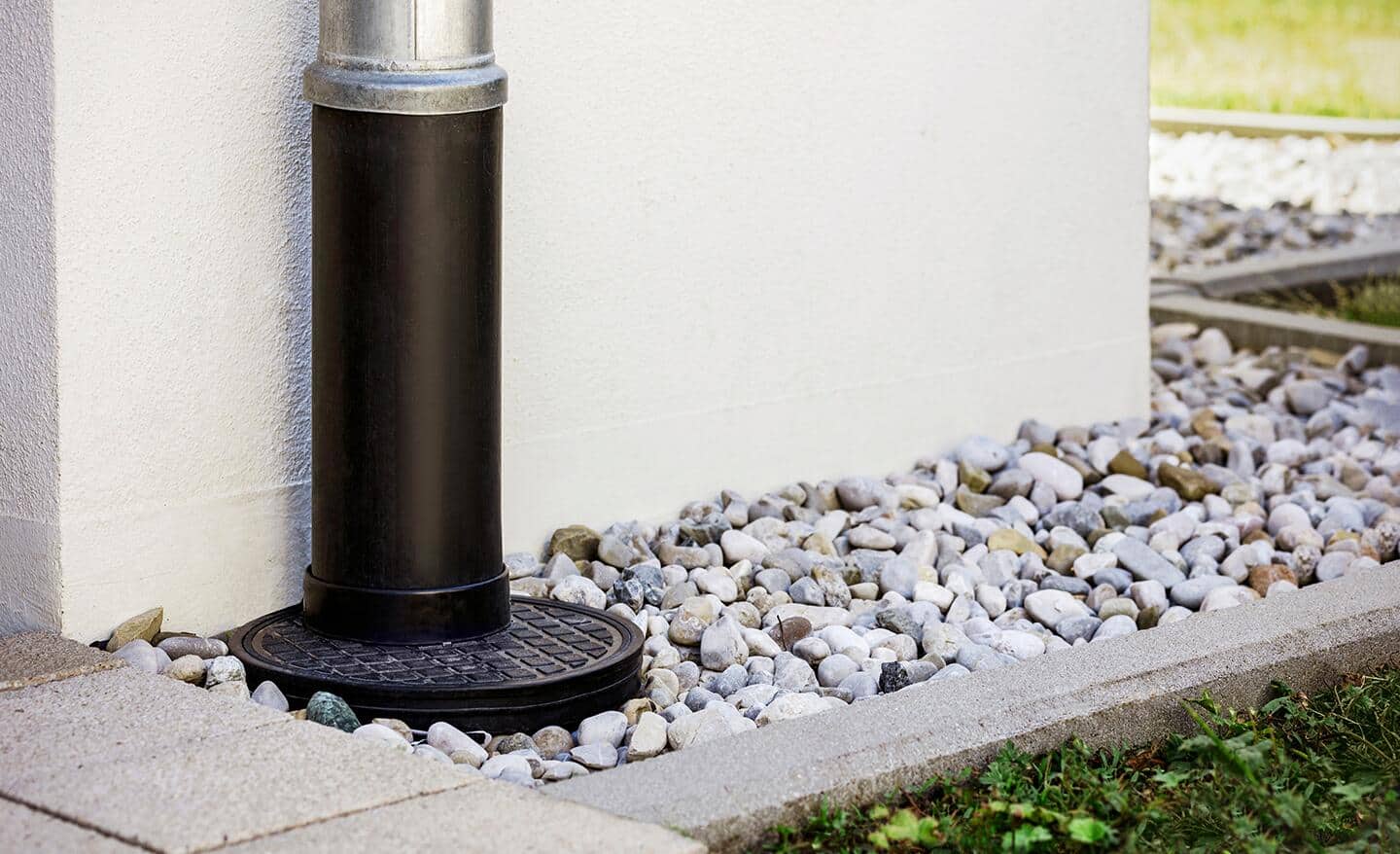 A French drain located next to a white wall. A French drain located next to a white wall.