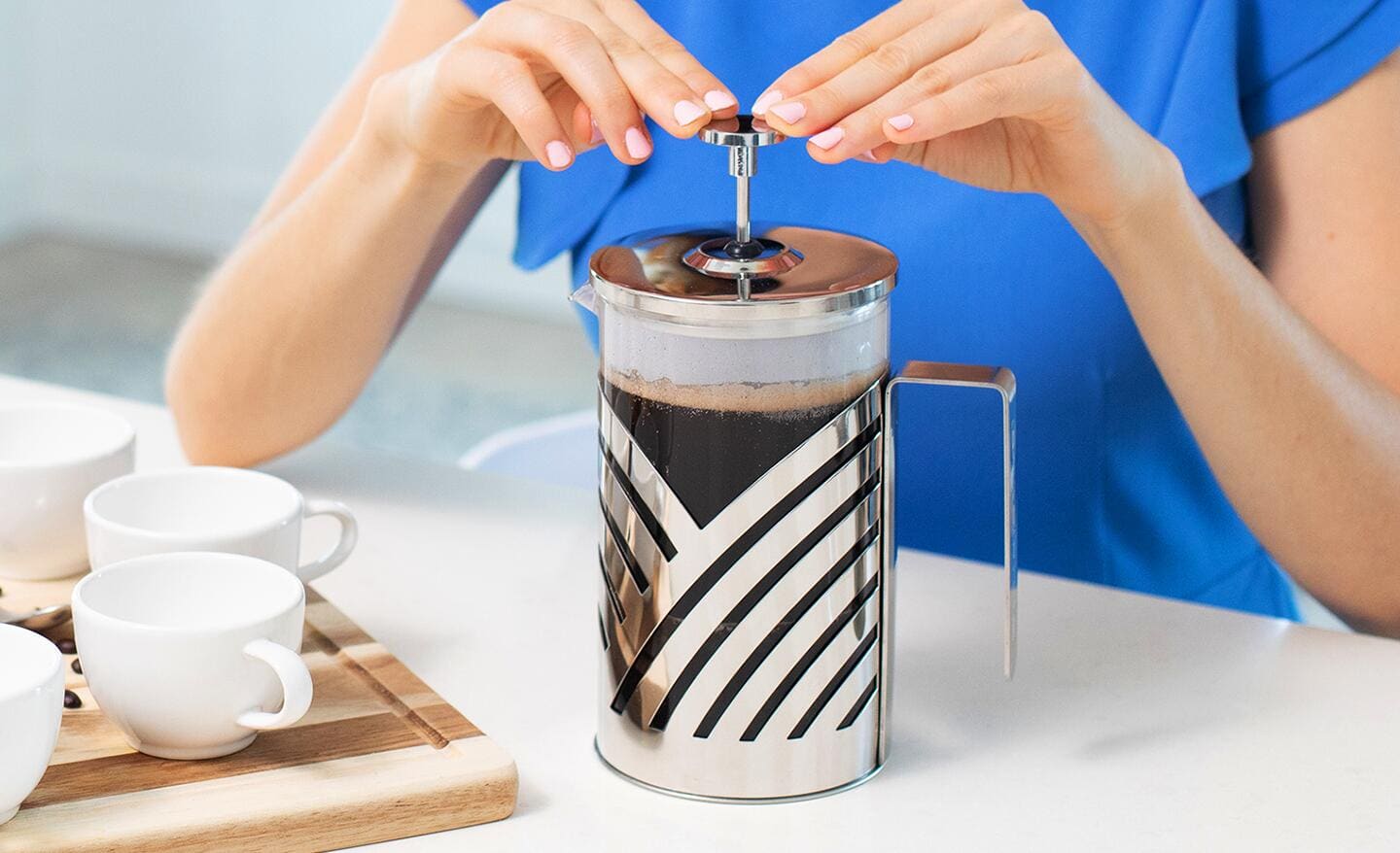A woman using a French press coffee maker. A woman using a French press coffee maker.