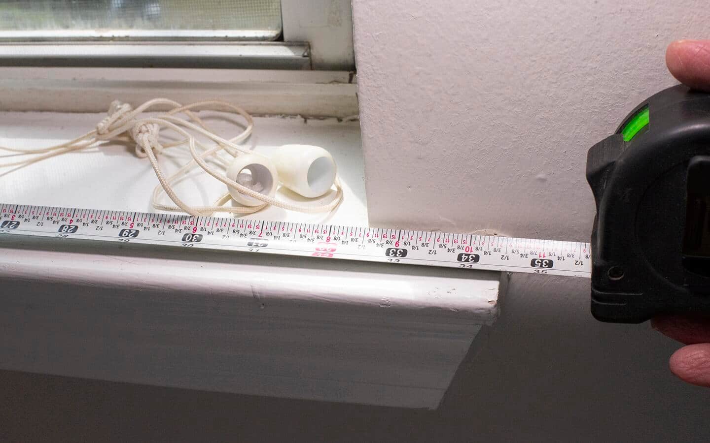 A tape measure is used to find the width of a windowsill.