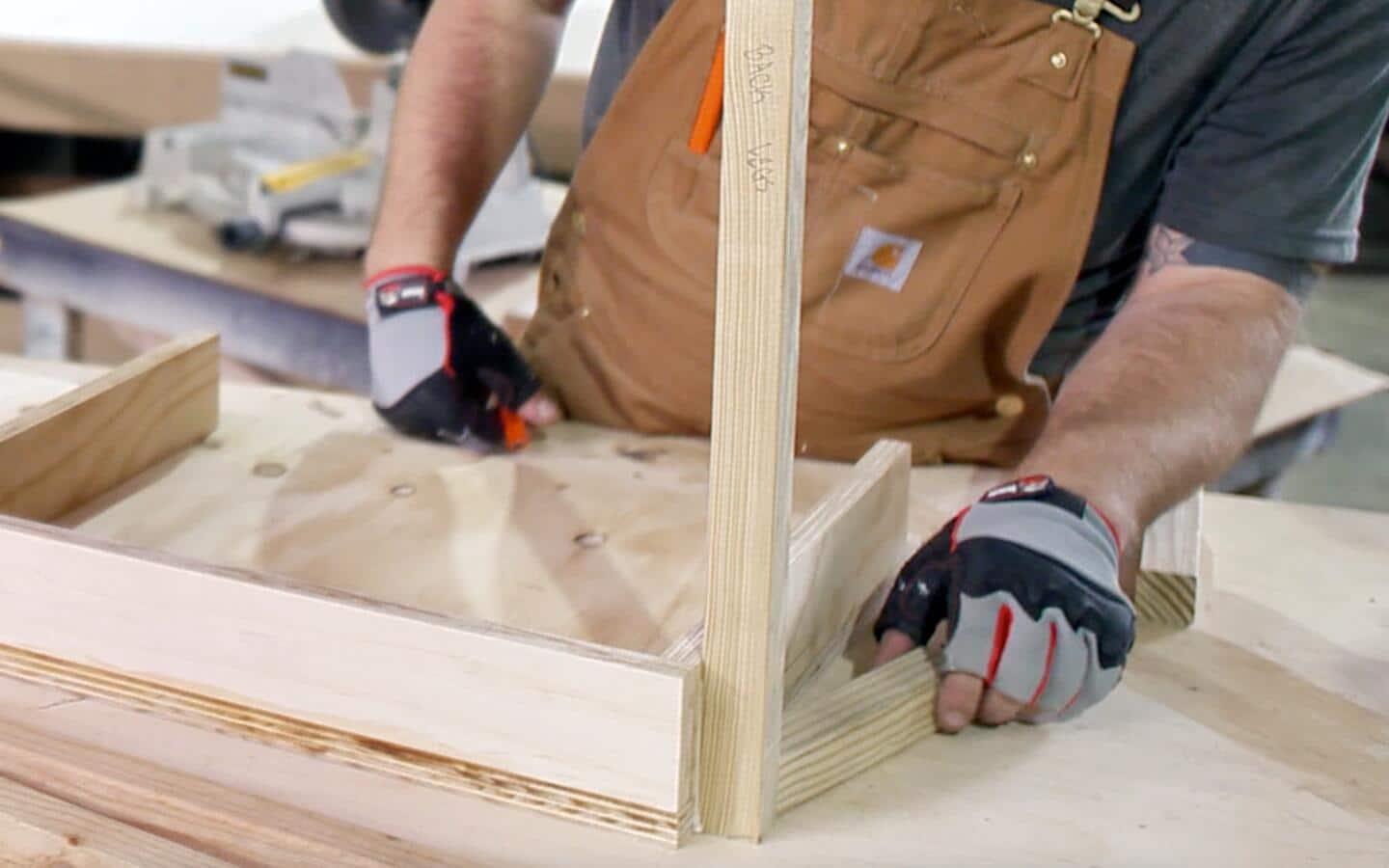 A person begins attaching legs to the wooden box of an upside-down DIY desk.