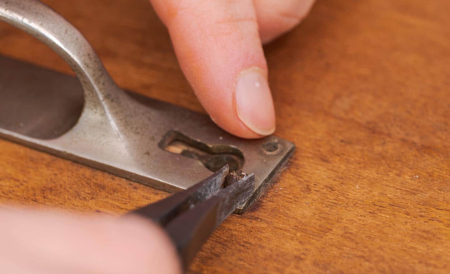 A person using a screw extractor to remove a broken screw. 