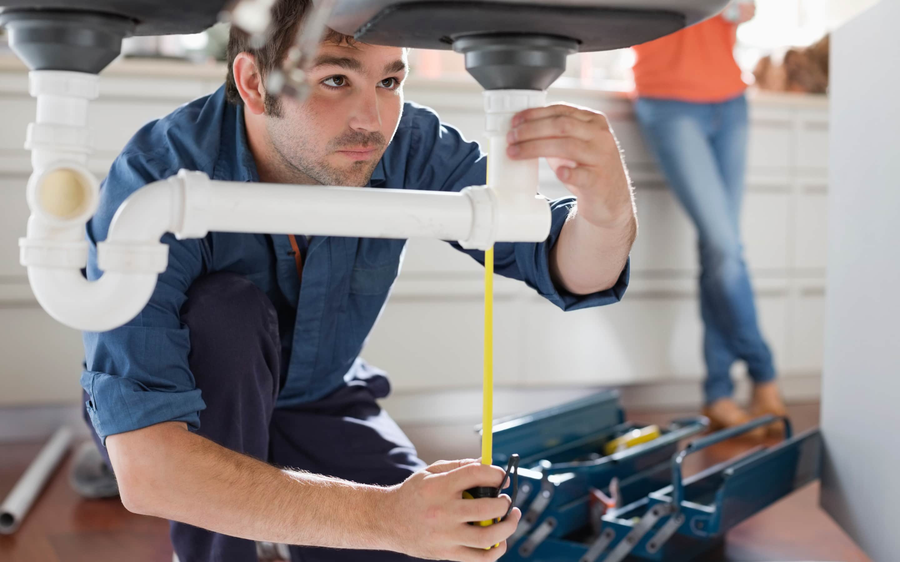 A plumber measures the height of a P-trap pipe. A plumber measures the height of a P-trap pipe.