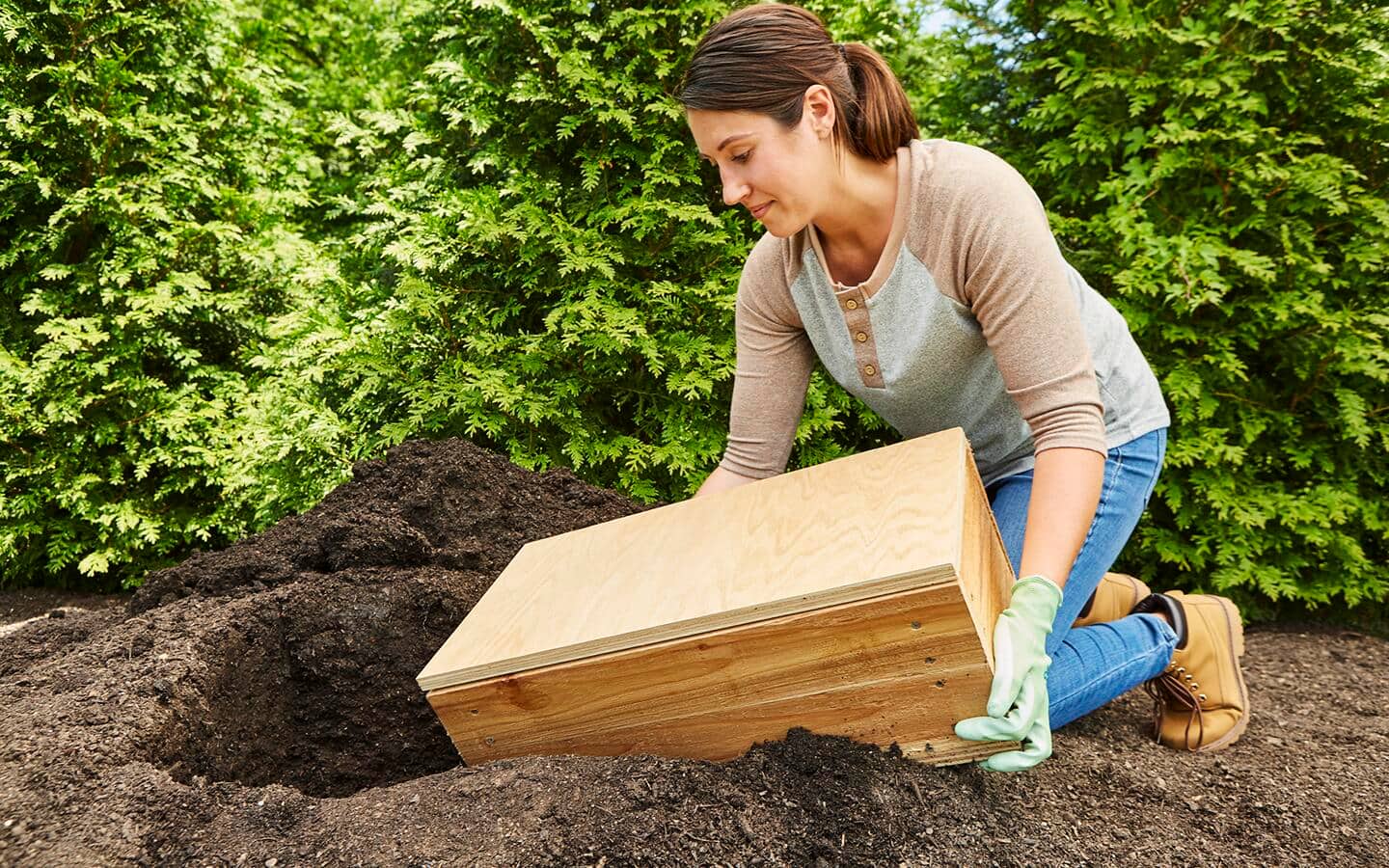 A person places a finished root cellar in a hole in the ground. A person places a finished root cellar in a hole in the ground.