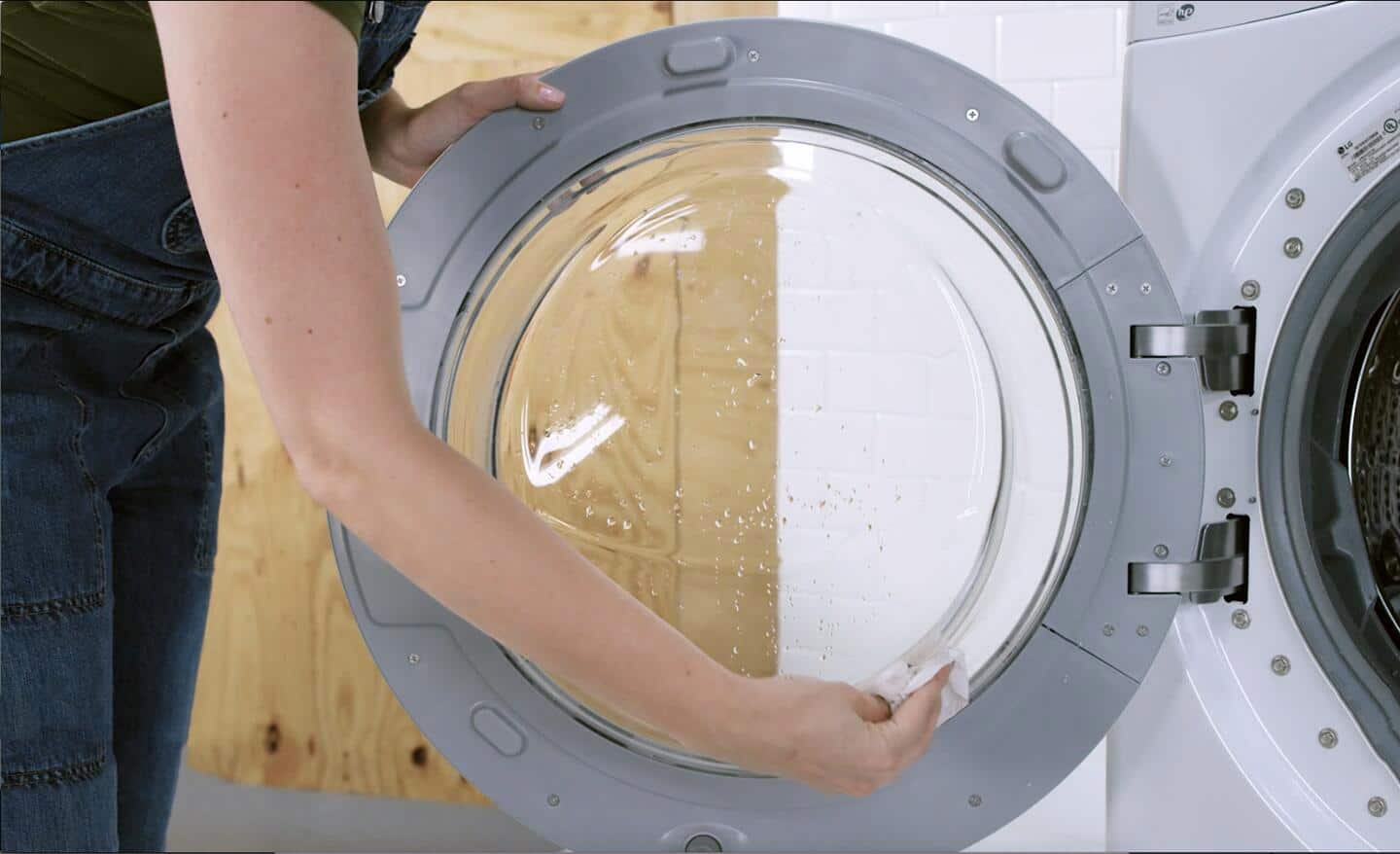 Someone cleaning the lid of a front load washer.