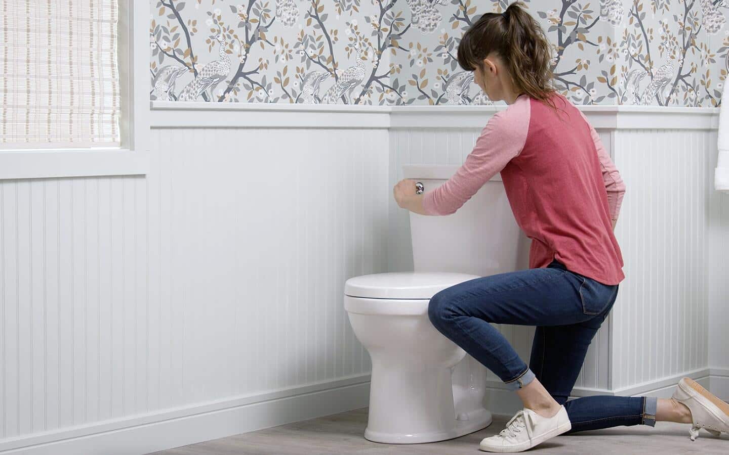 A woman about to remove a toilet tank cover. A woman about to remove a toilet tank cover.