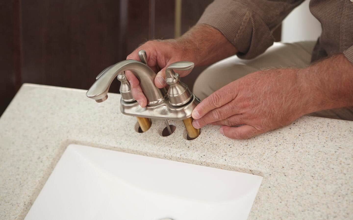 Someone removing a two-handled faucet from a sink. Someone removing a two-handled faucet from a sink.