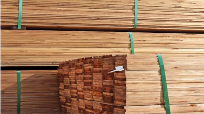 Stacks of framing lumber stand in a warehouse.