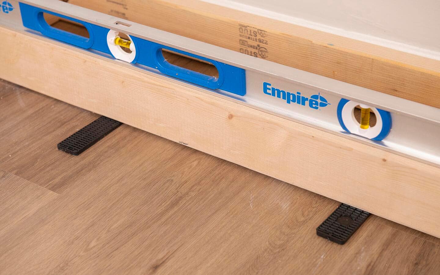 A level and shims being used to adjust the base of a built in shelving unit.