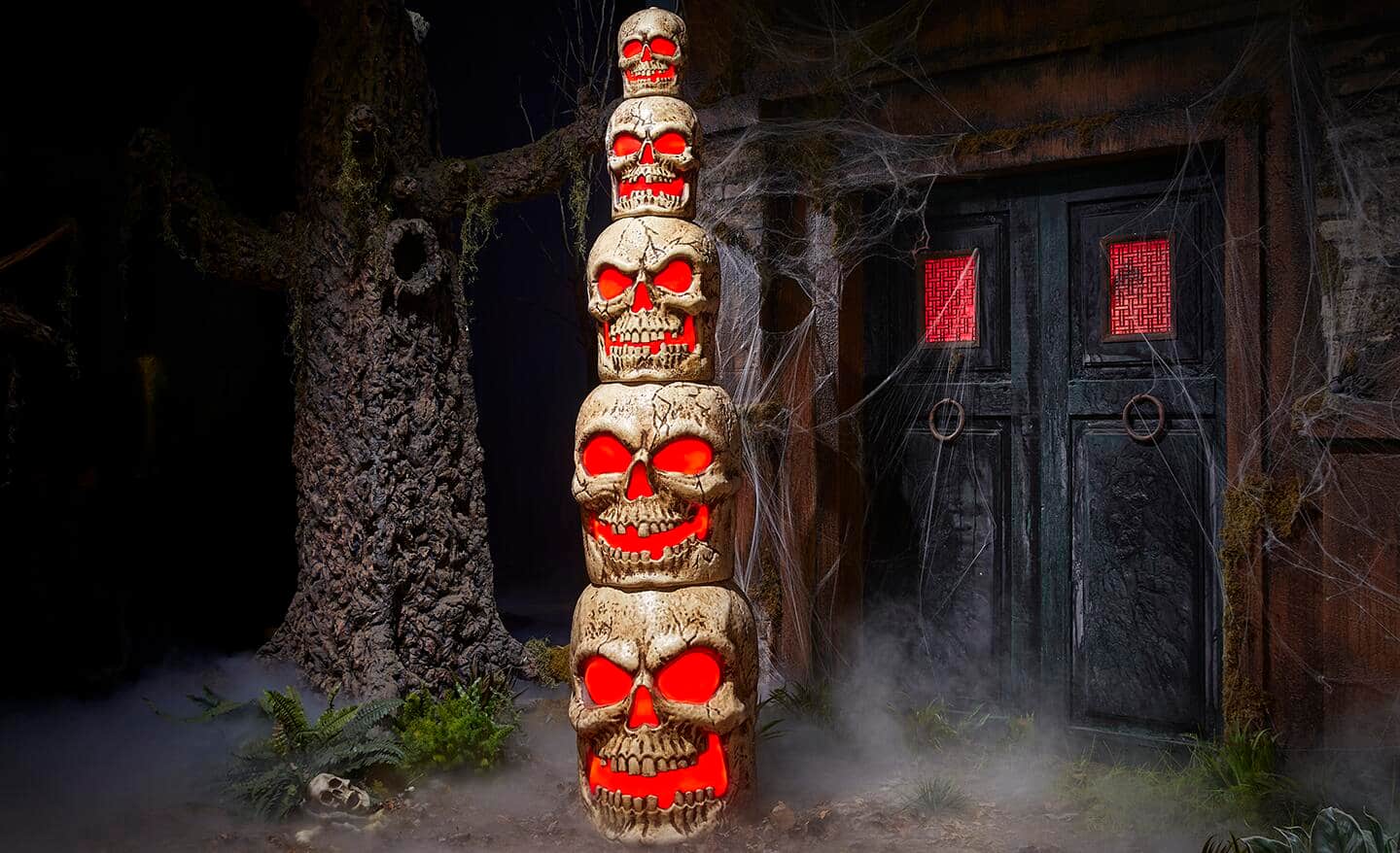 A stack of skulls with glowing red eyes and mouths stand in a spooky scene.
