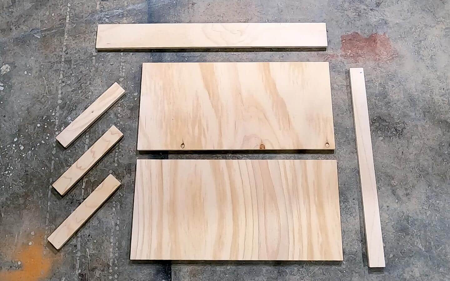 Various sizes of cut plywood laid out for a DIY desk project.