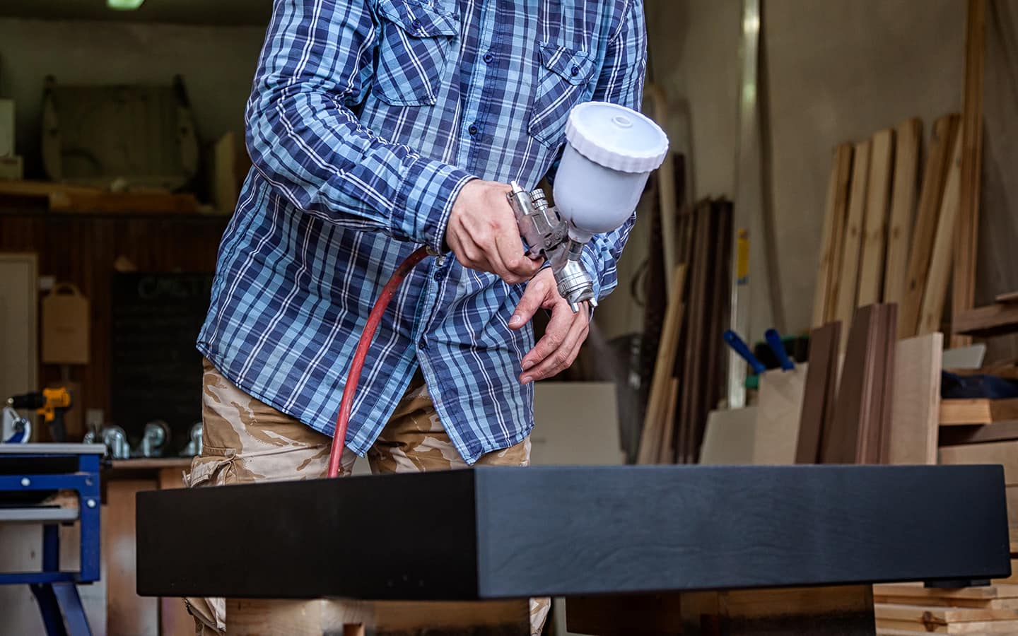 A person spray painting wood.