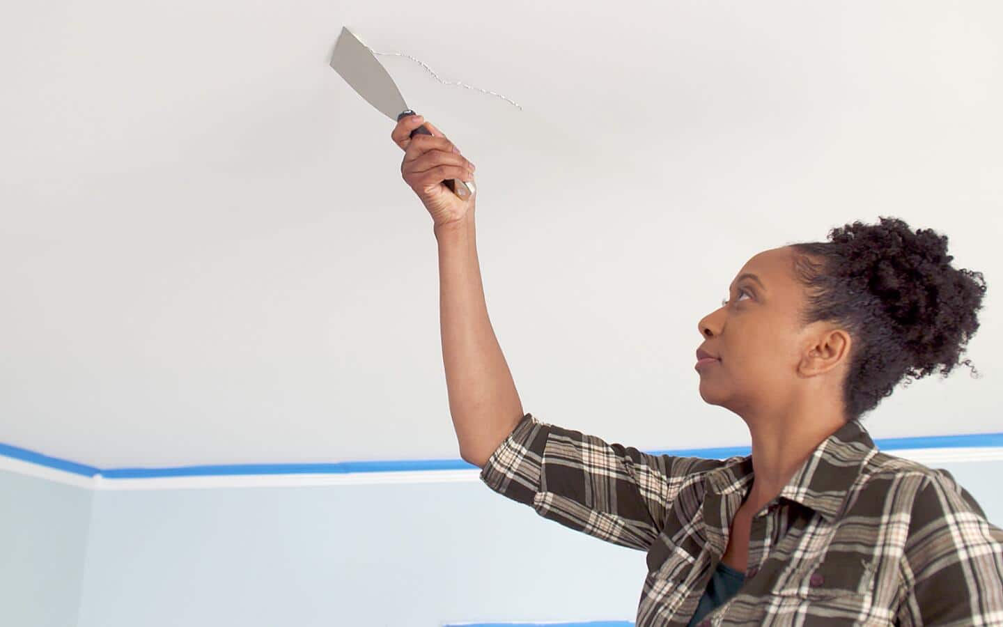A person uses a paint scraper to apply paint to repair a ceiling. A person uses a paint scraper to apply paint to repair a ceiling.