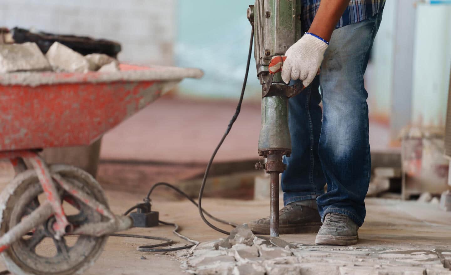 A Pro uses a jackhammer in a basement.