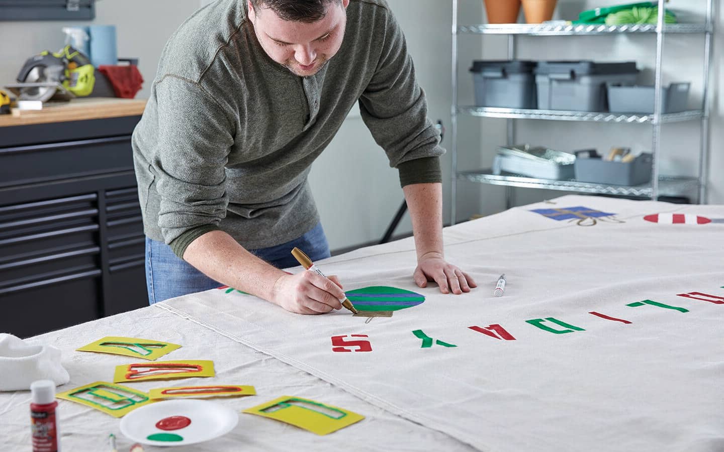 A man uses a paint pen to add a detail to a ornament painted on a canvas backdrop. A man uses a paint pen to add a detail to a ornament painted on a canvas backdrop.