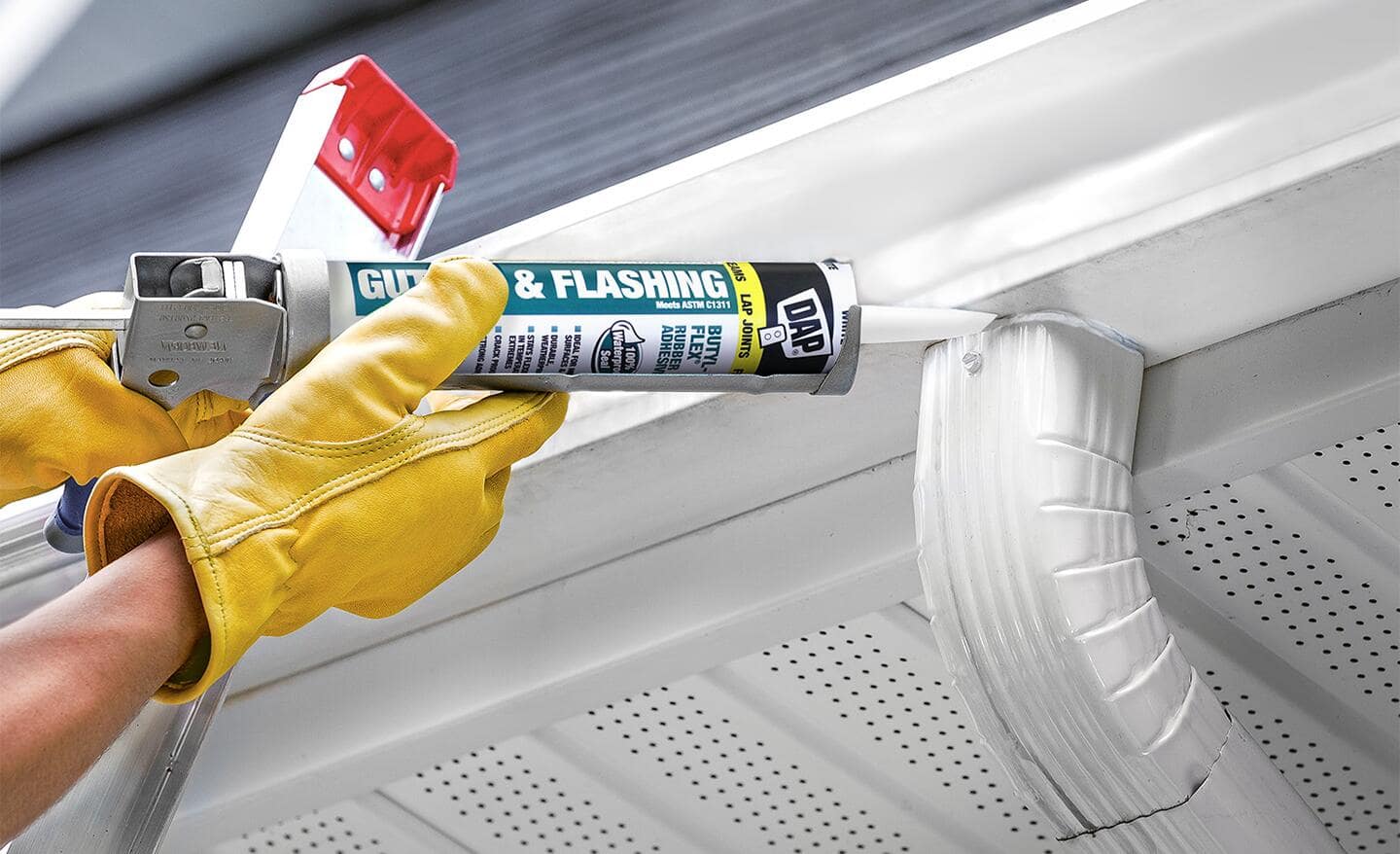 Person using a caulk gun with butyl-rubber cartridge to seal a rain gutter Person using a caulk gun with butyl-rubber cartridge to seal a rain gutter
