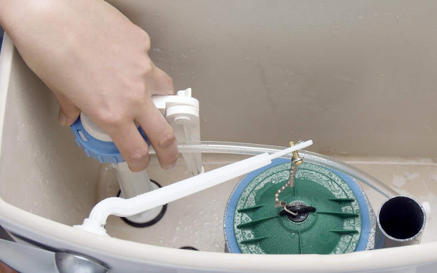 A person removing an old fill valve. A person removing an old fill valve.