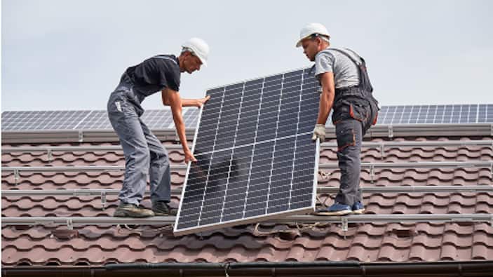 Two Pros install solar panels on a roof.