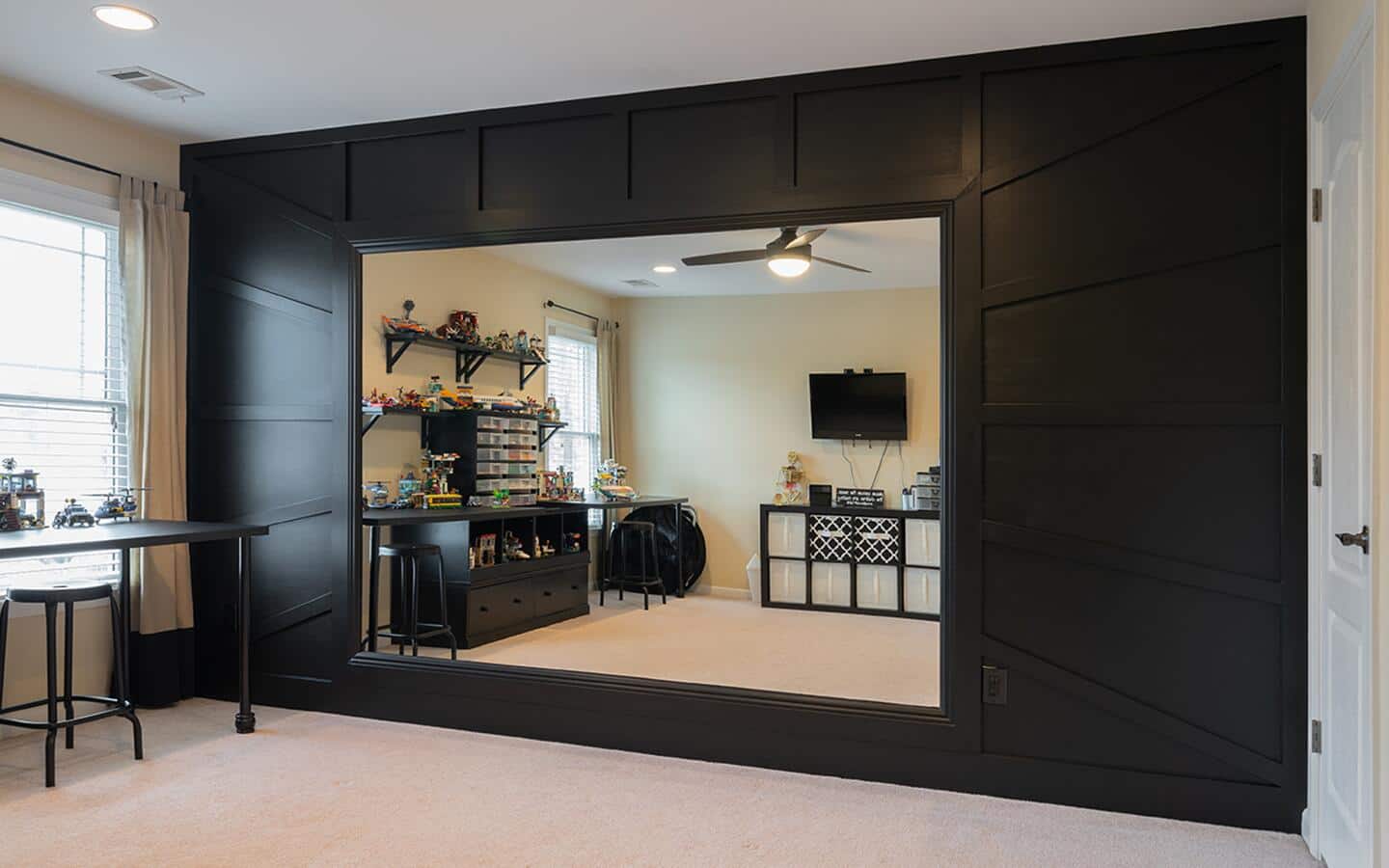 A large wall mirror reflecting shelves and furniture in a den.