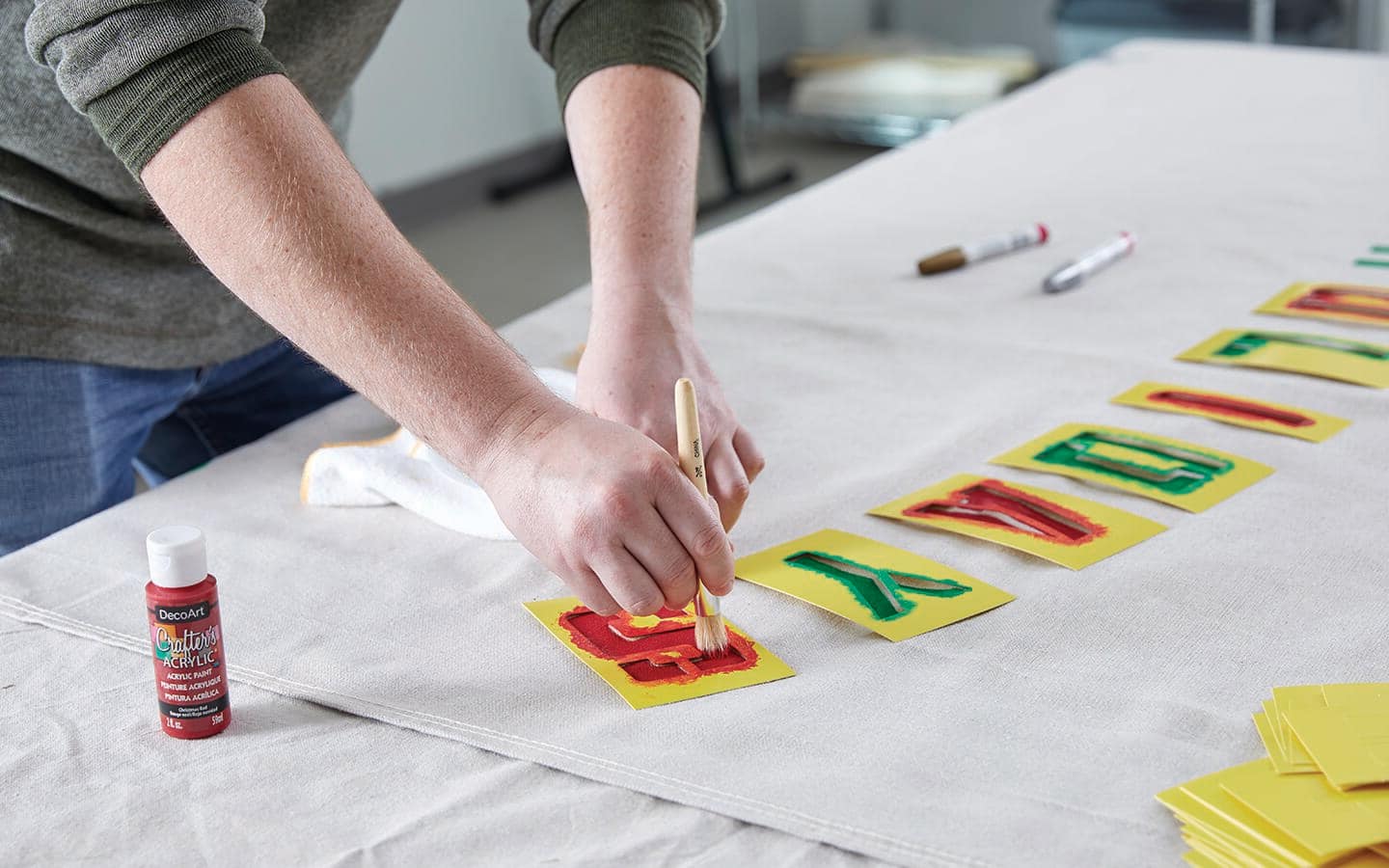 Someone uses a brush, paint and stencils to add letters to a piece of canvas. Someone uses a brush, paint and stencils to add letters to a piece of canvas.