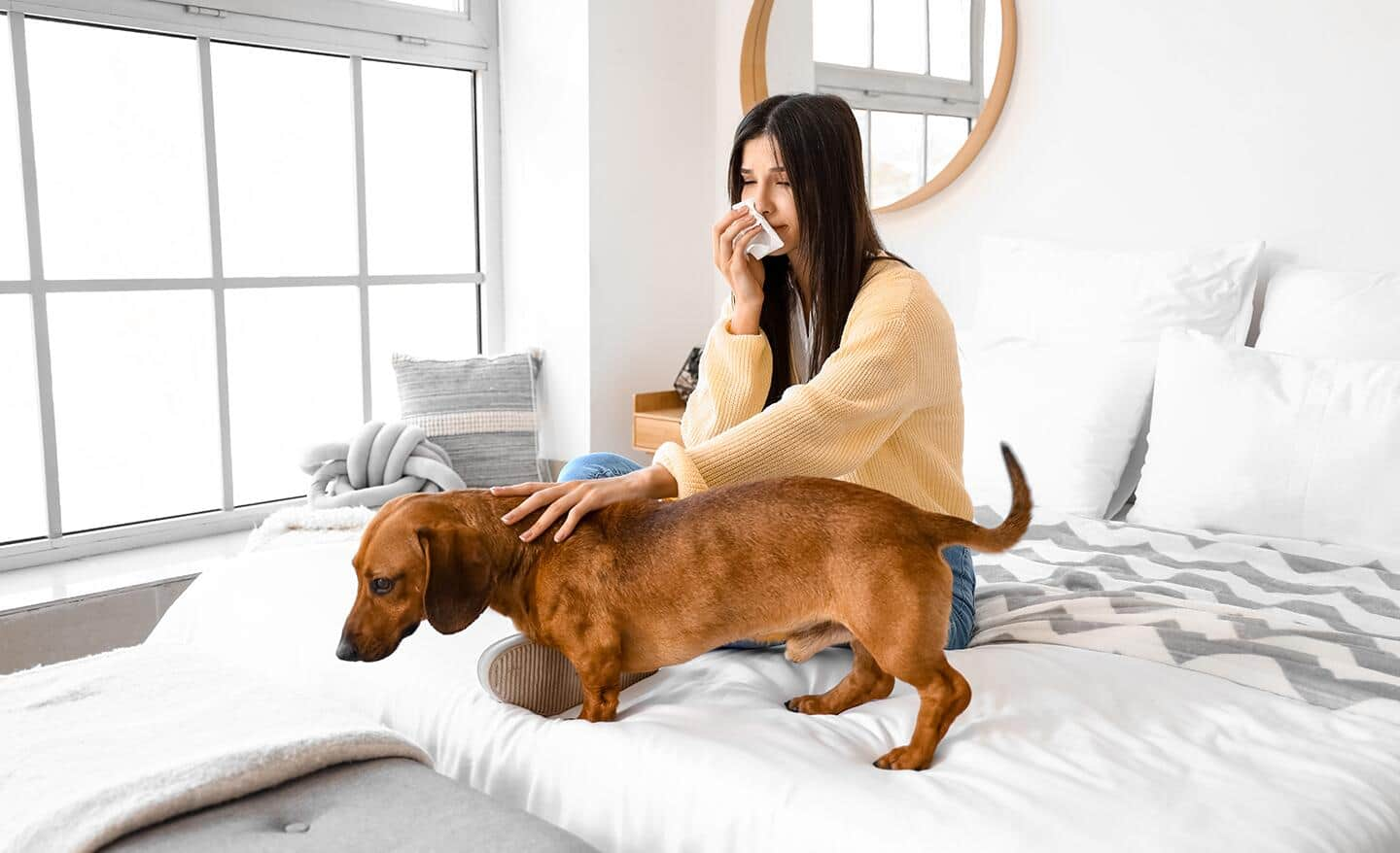 A woman sitting on her bed with her dog.