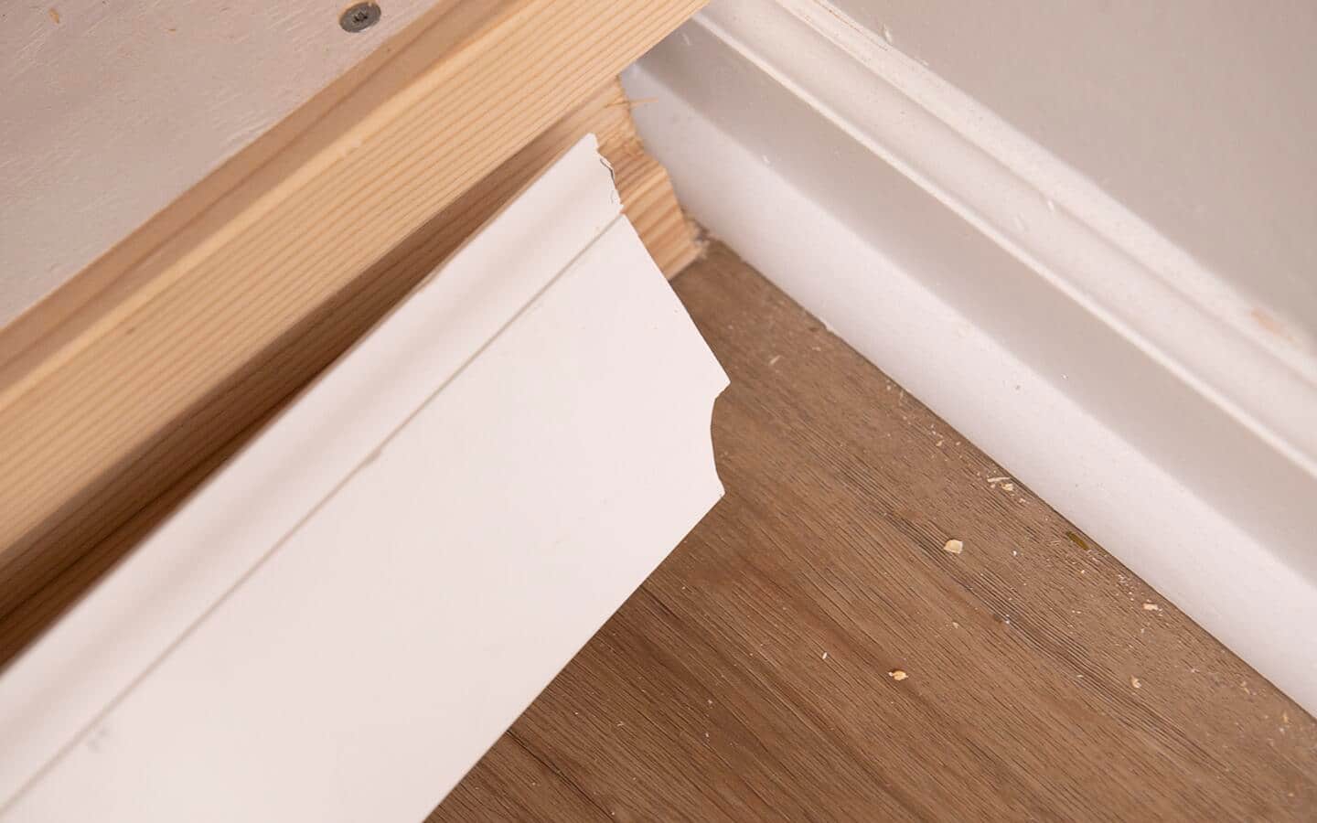 The baseboard is coped in a shape that fits the profile of the existing trim.