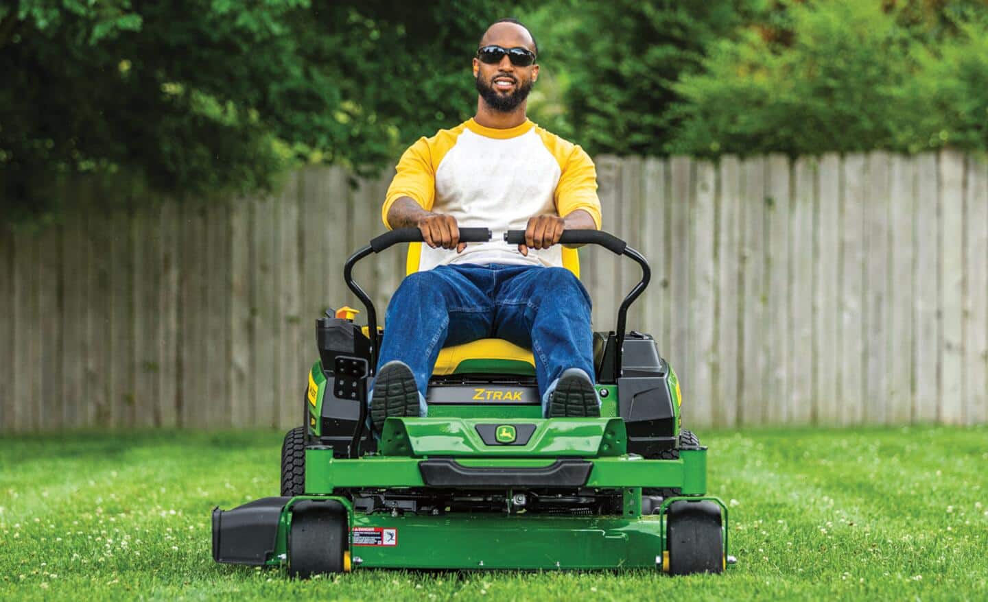 A man wears safety goggles to use his riding mower.