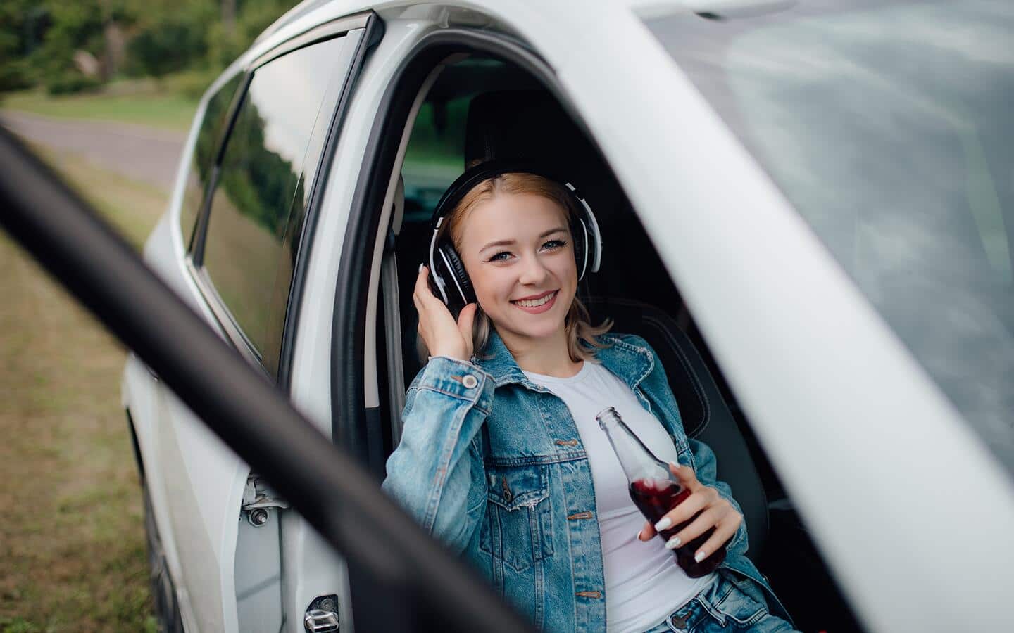 A person wearing headphones in a car's passenger seat. A person wearing headphones in a car's passenger seat.