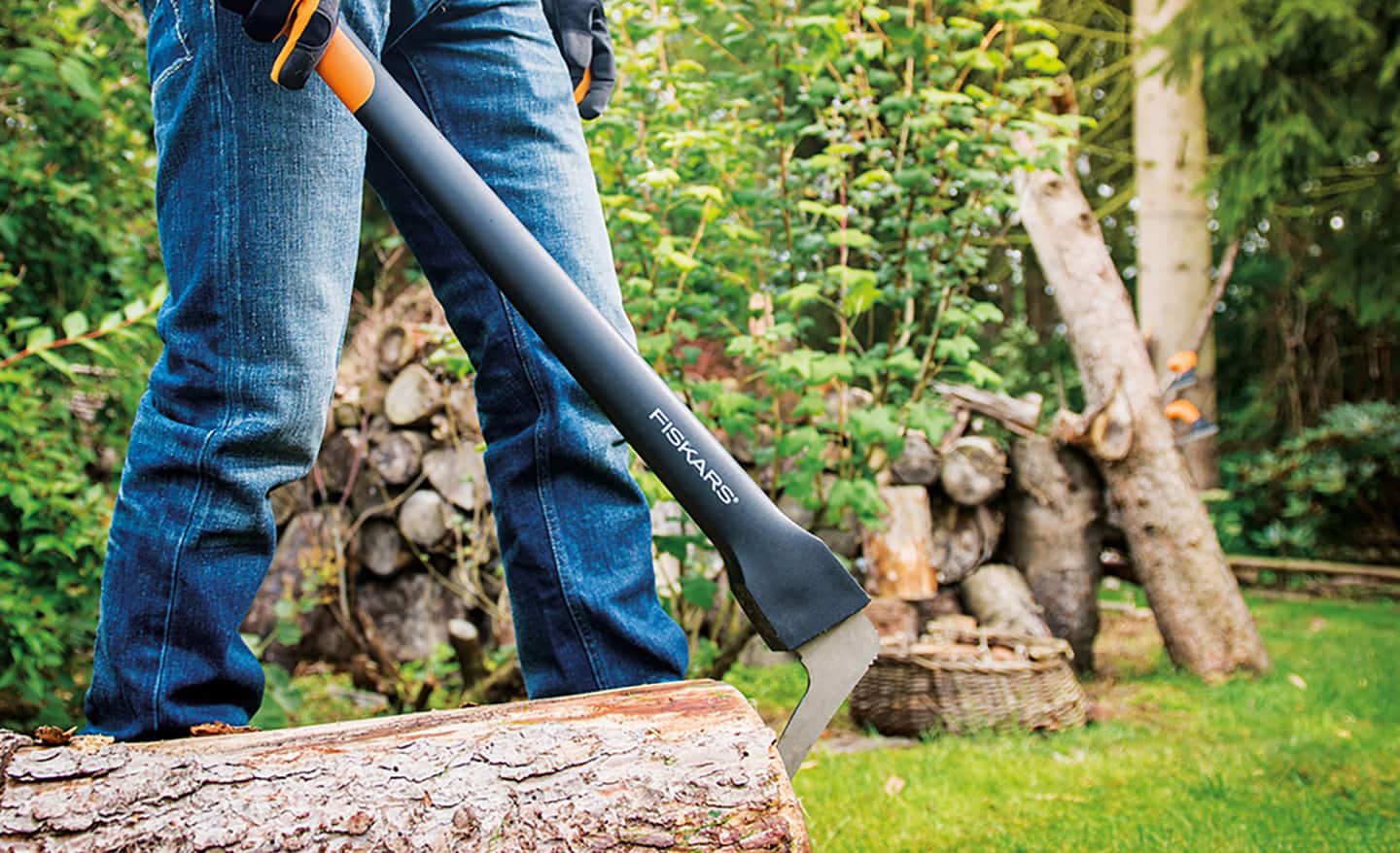 A man uses an axe striking tool to split wood and for yard work.