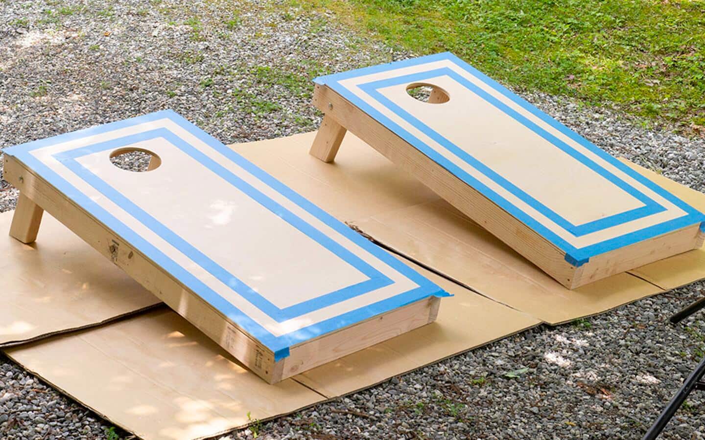 Cornhole game boards placed outside on cardboard for painting. Cornhole game boards placed outside on cardboard for painting.