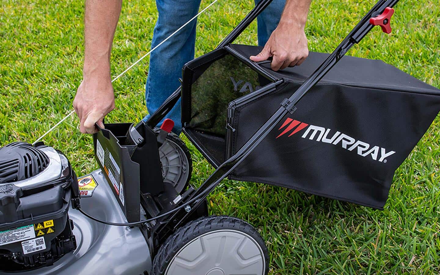 Someone empties the bag of a push mower that automatically collects clippings. Someone empties the bag of a push mower that automatically collects clippings.