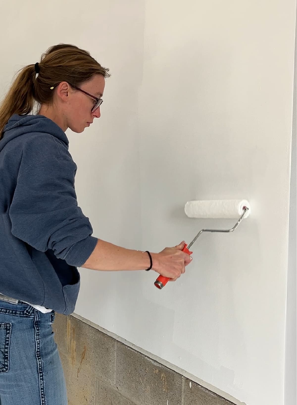 Woman painting a wall white. 