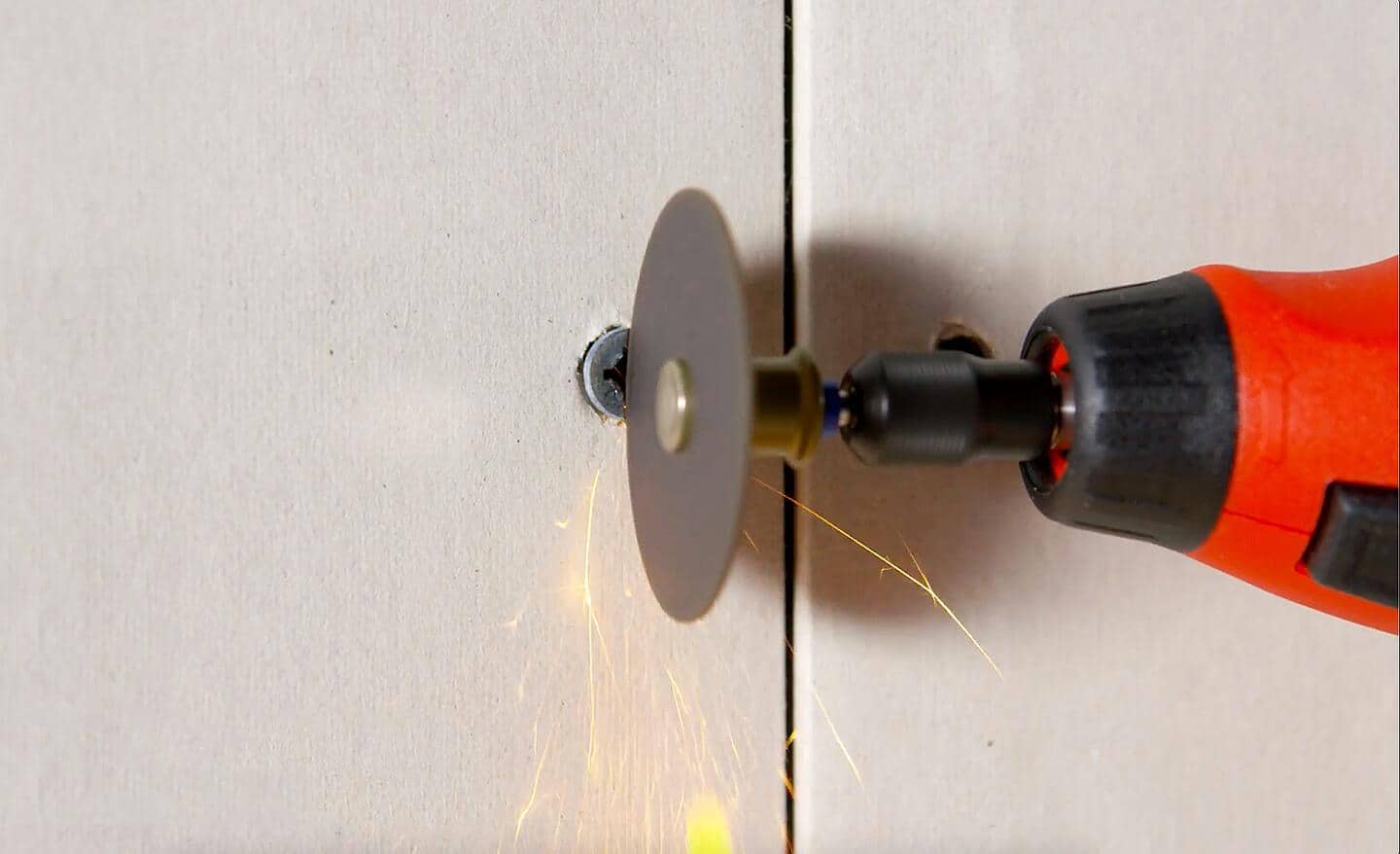 Small saw cutting into a screw in a wall.