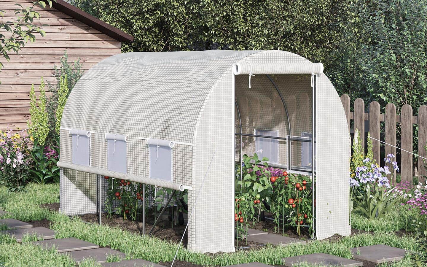 A greenhouse structure with plants inside on a base of mulch and pavers