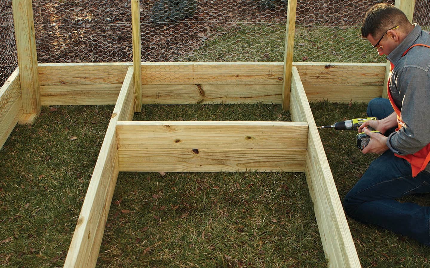 An individual uses a cordless drill to attach wooden boards for a garden bed. An individual uses a cordless drill to attach wooden boards for a garden bed.