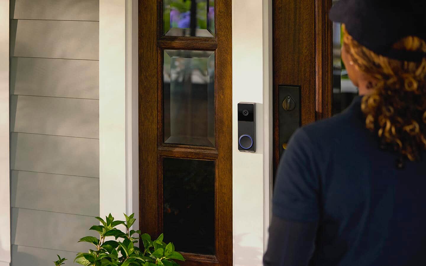 A delivery person approaching a video doorbell installed on a home. A delivery person approaching a video doorbell installed on a home.