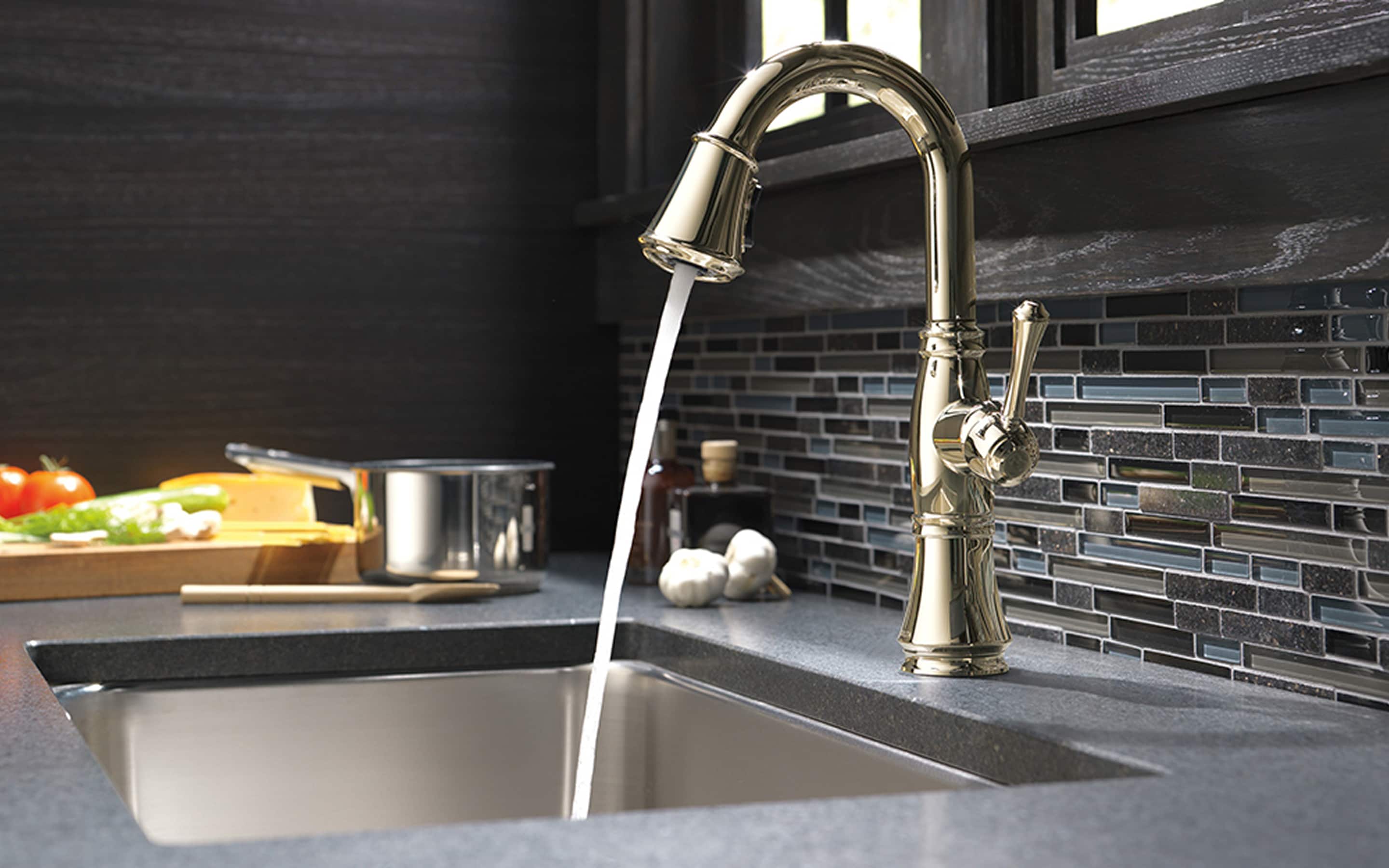 Water from a kitchen faucet running into a sink where a garbage disposal is installed.