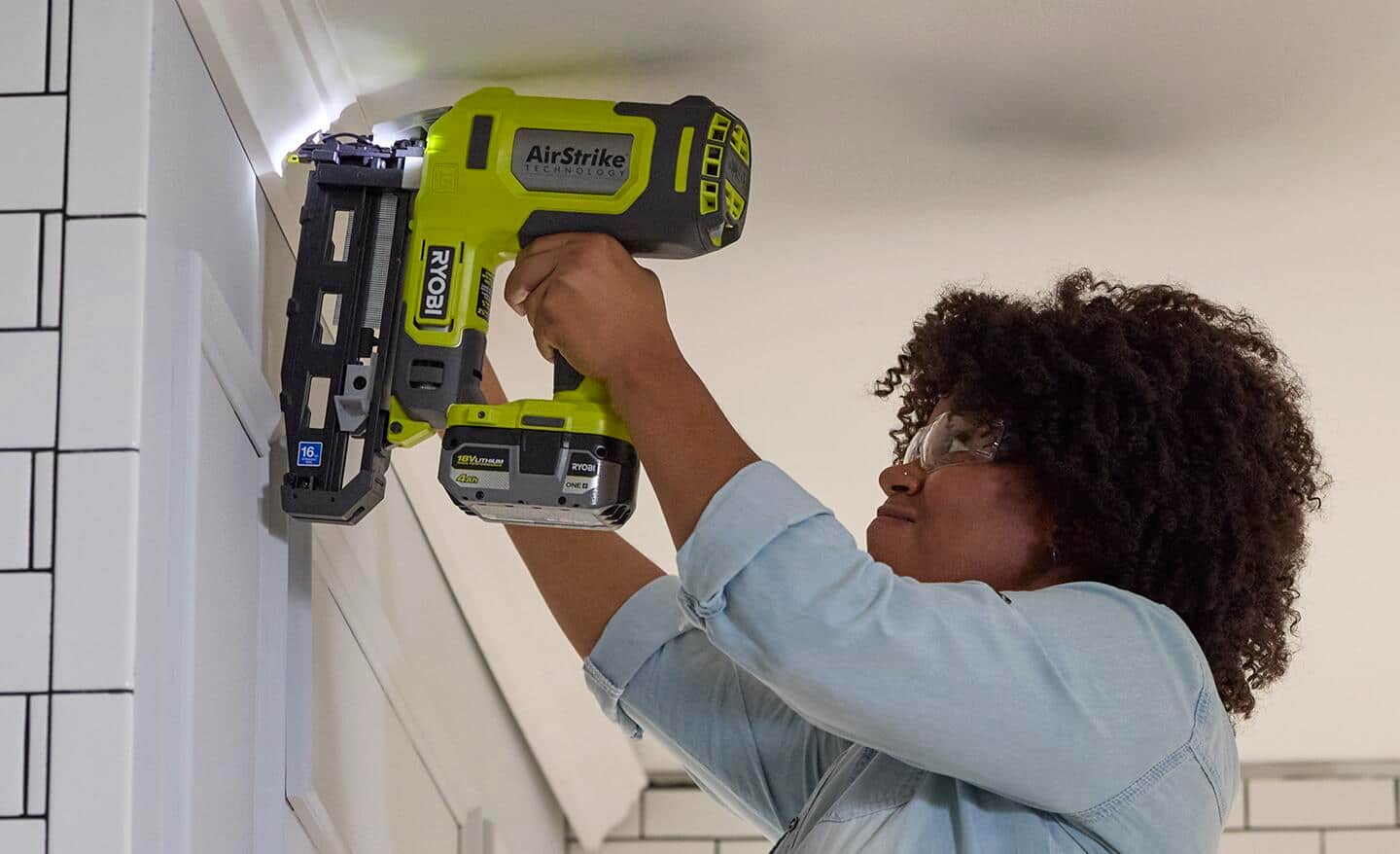 A person nailing moulding to the wall using a finish nailer.